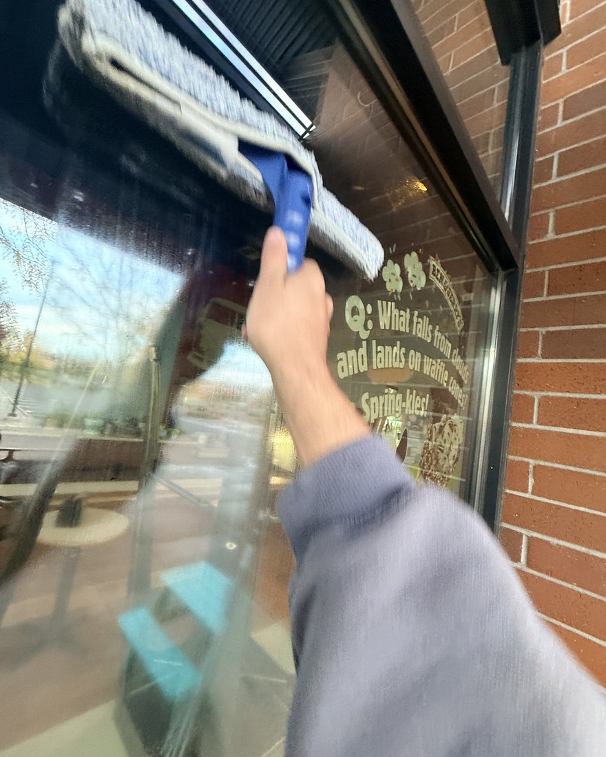 Kai squeegeeing a storefront window in downtown Bend