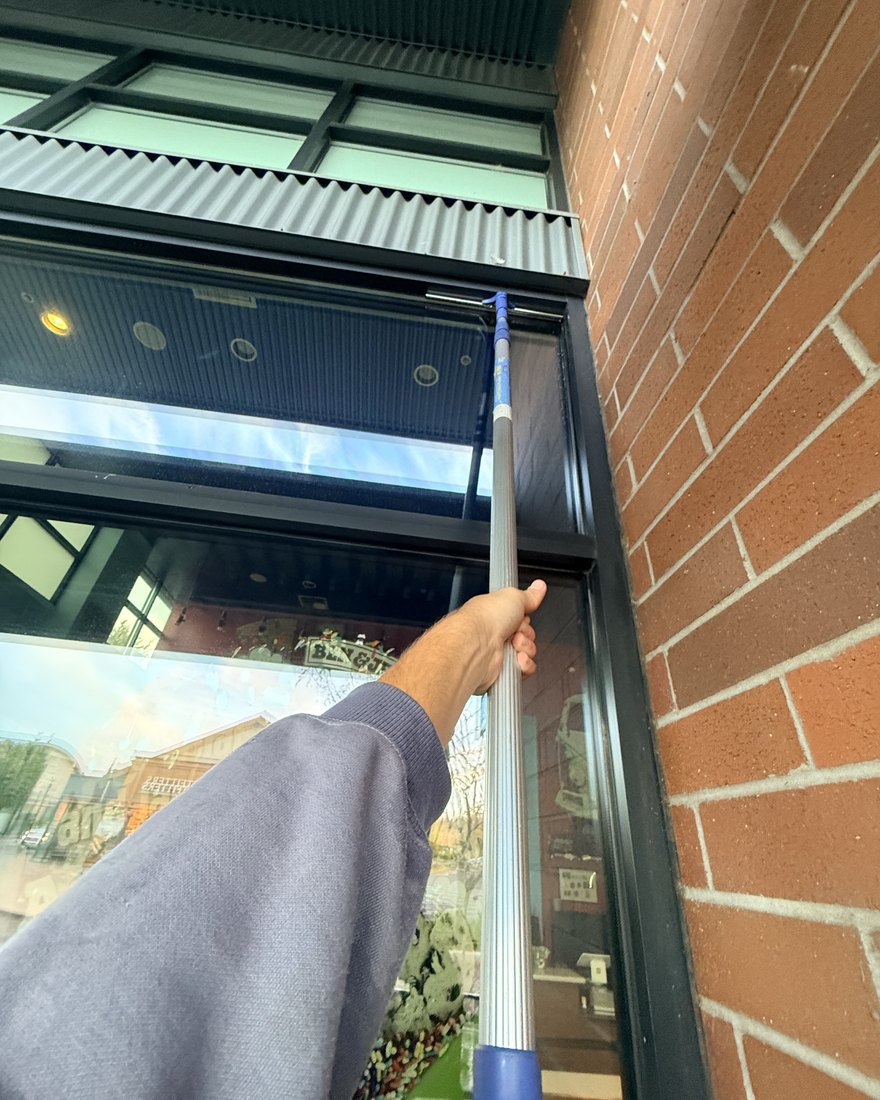 Washing a commercial storefront with an extension pole in downtown Bend