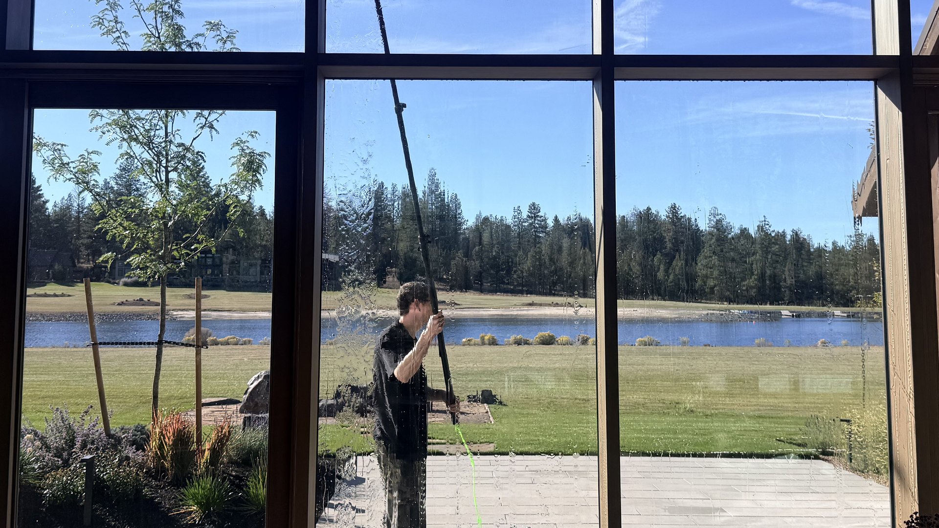 Water-fed pole washing floor-to-ceiling glass at a lakeside home in Bend